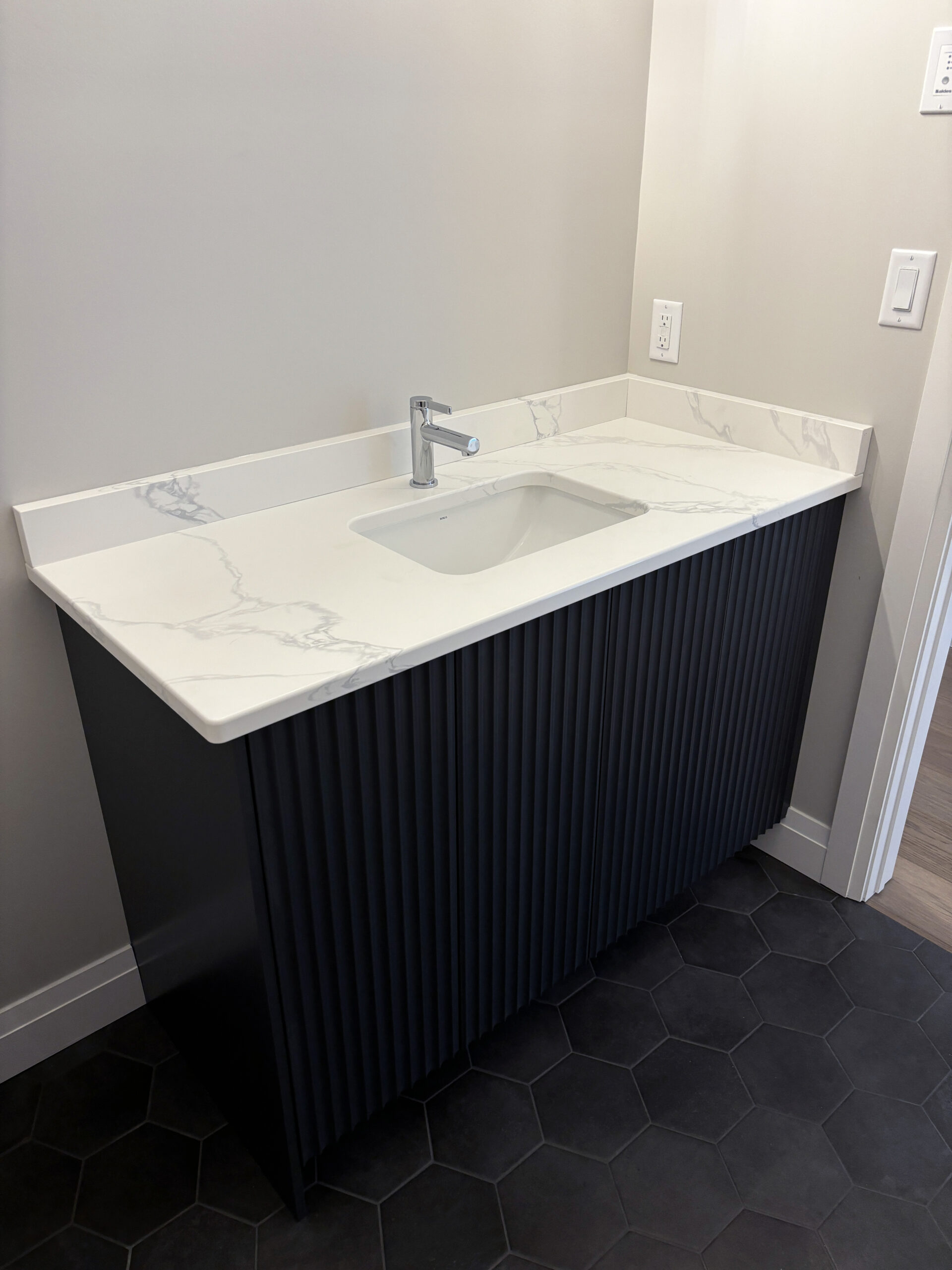 Black fluted floating bathroom vanity with white marble top, built in Sudbury by Canarini Kitchens